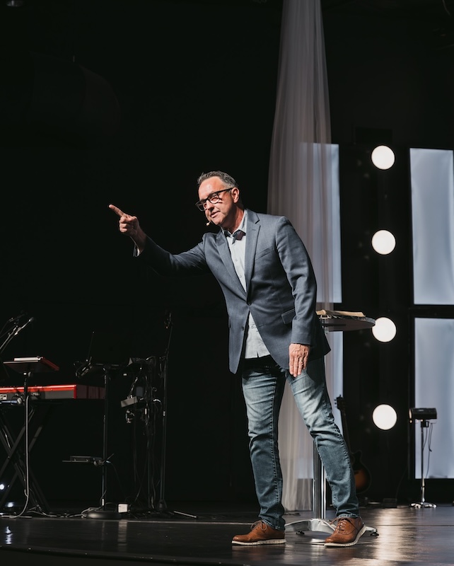Pastor teaching from an open Bible on stage during a Sunday service at Stone Edge Church