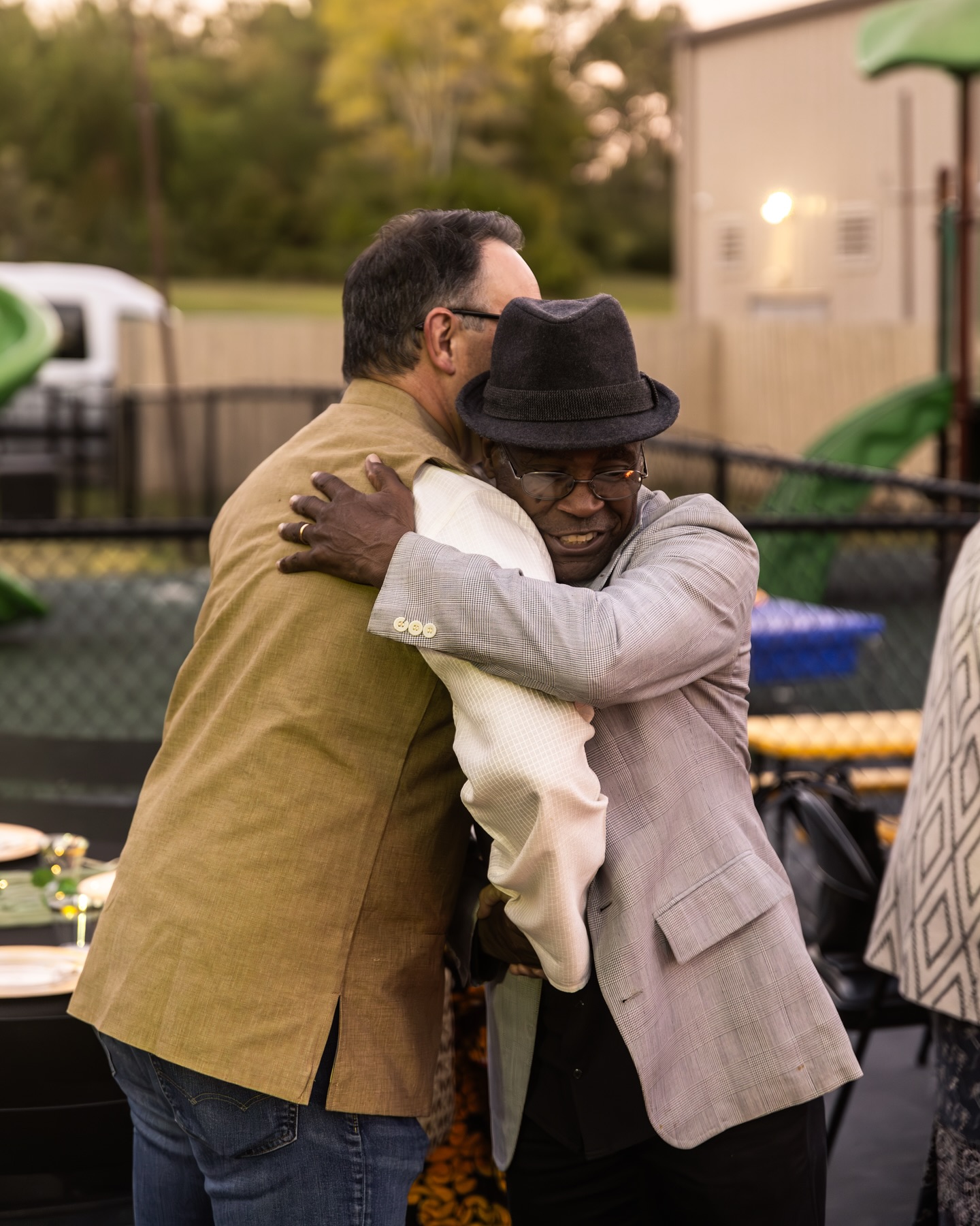 Two men sharing a warm hug at an outdoor Stone Edge Men gathering
