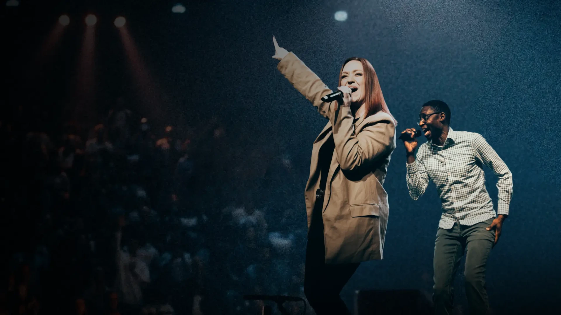 Two worship leaders singing on stage during a Sunday service at Stone Edge Church